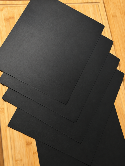Five black BBQ grill mats on a bamboo board